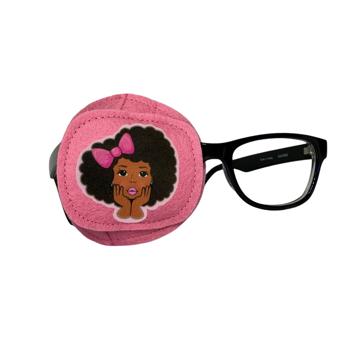 Pink wool felt eye patch with embroidered portrait of a girl with afro and pink bows, shown on glasses frame